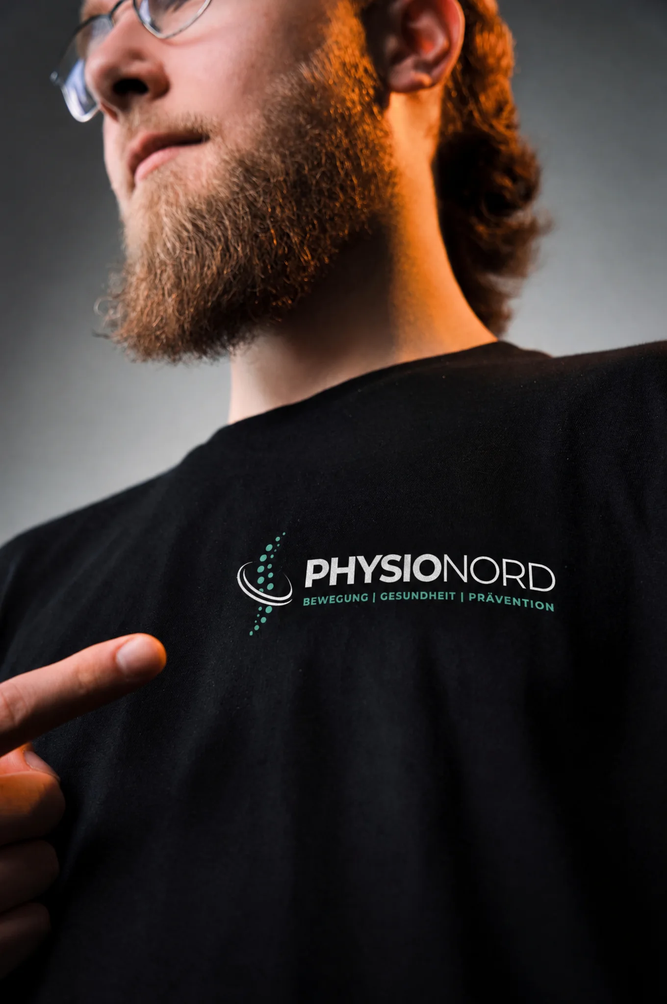 Emrullah Demir zeigt auf das neue PhysioNord-Logo auf seinem Shirt
